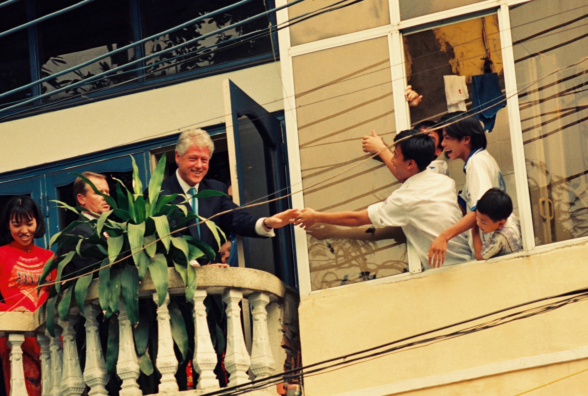 President Bill Clinton shoke hand with a bunch of Vietnamese teenagers over an old window in Hanoi.
